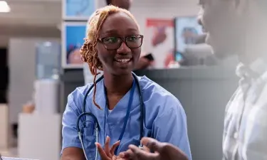 Massachusetts medical assistant smiling and discussing treatment with patient in clinic